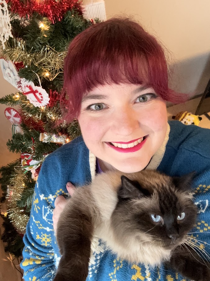Erin holds Ciri the cat in front of a Christmas tree